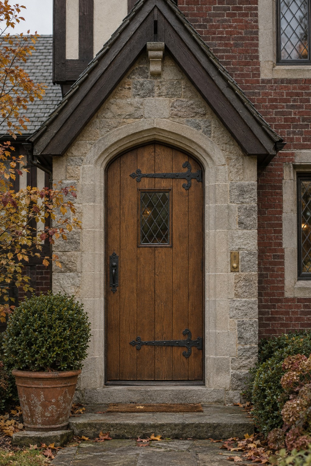 Arched oak front door with iron strap hinges and a speakeasy grille, a custom wood entry for a Tudor Revival home.